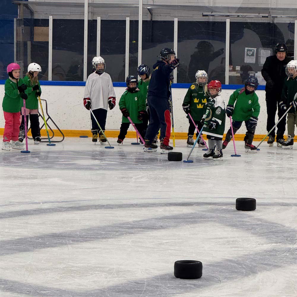 Barn tränar ringette och skridskoåkning tillsammans med ledare